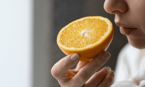 Woman smelling a sliced orange close up. Using all your senses. Eating more mindfully. Veg Out With Maria
