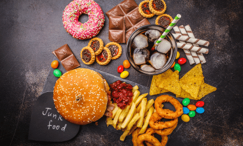 junk food: fast food and sugar. Burger, chips, sweets, soda, french fries, onion rings, doughnut on a dark background. Foods that cause inflammation.