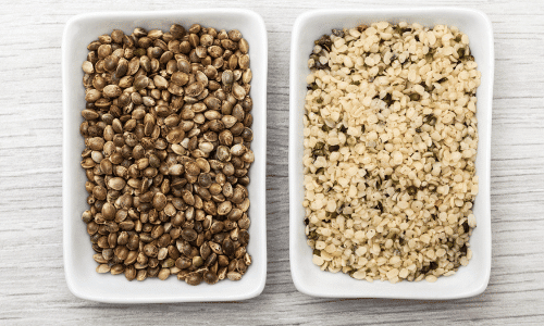 A picture of hemp seeds on the left and hemp hearts on the right, both in a white bowl on a white-washed table.