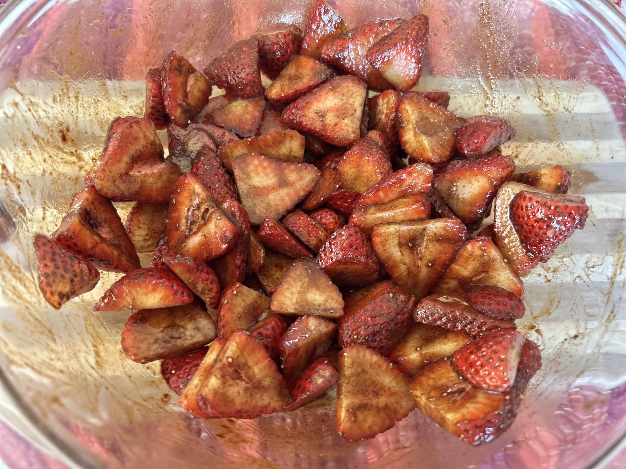 sliced strawberries in bowl with balsamic vinegar and cinnamon mixed in