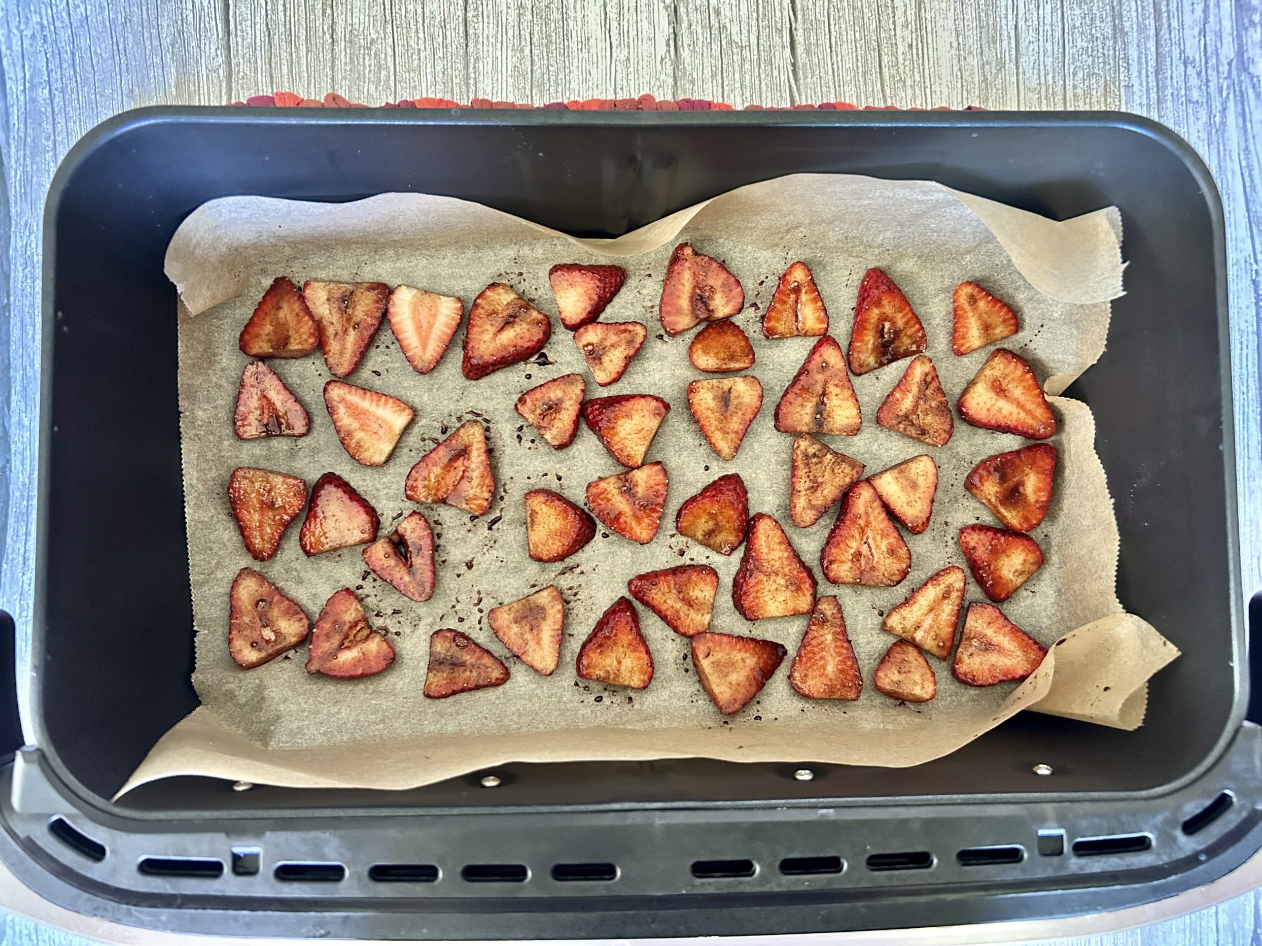 balsamic and cinnamon sliced strawberries lined on parchment paper in air fryer