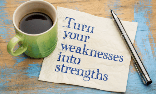 picture of a cup of coffee and pen on a wood table top with a napkin reading "Turn Your Weaknesses Into Strengths." Benefits of drinking coffee on a plant-based diet. 