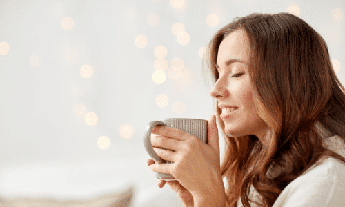 happy woman holding cup of coffee. benefits of drinking coffee on a plant-based diet.