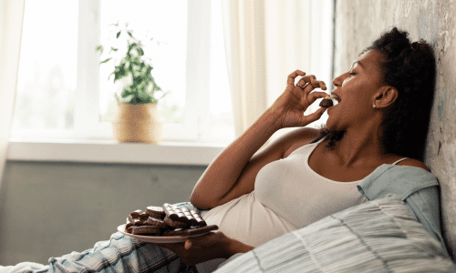 Woman Eating Chocolate Candies on Her Bed. Dark Chocolate and Menopause.
