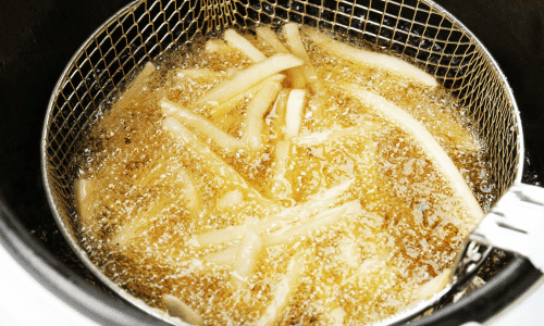 close up of French fries frying in seed oil