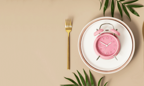 picture of a pink clock on a white plate. Time restricted eating.